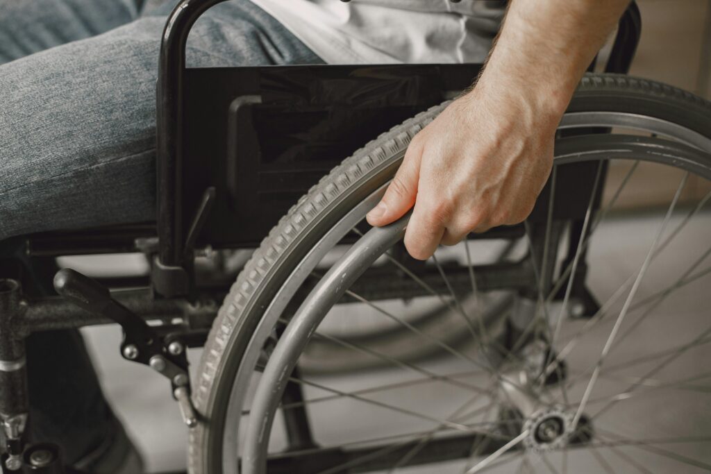 A close-up image showing a hand gripping a wheelchair wheel, portraying mobility and accessibility.